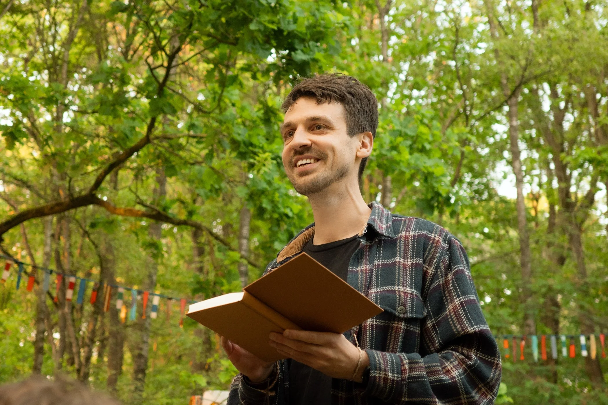 Jorim leest buiten tussen de bomen voor uit een boek